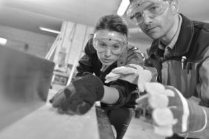 two people in safety wear cutting wood
