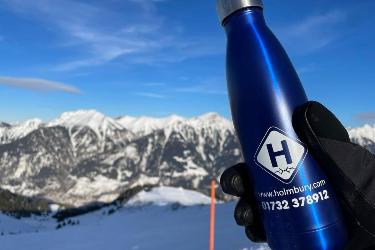 holmbury drinking bottle held by gloved hand with snowy mountains in background